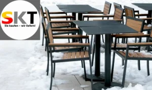 Auf dem zugeschneiten, gefroeren Boden aus Platten, stehen Tische und Stühle.